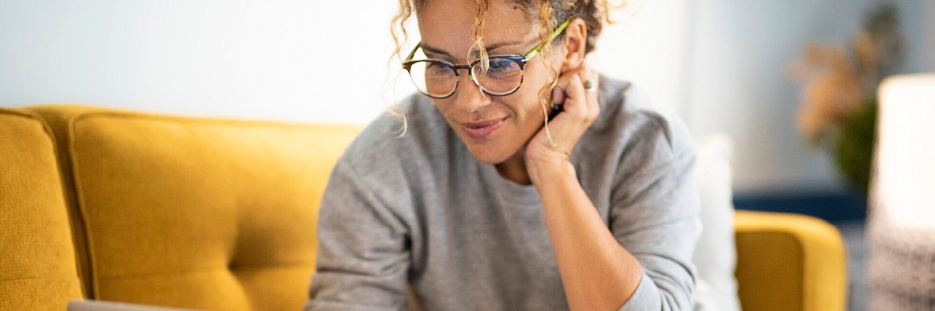 Female adult sat on the sofa reading on a laptop